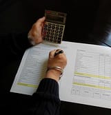 woman writing and holding calculator
